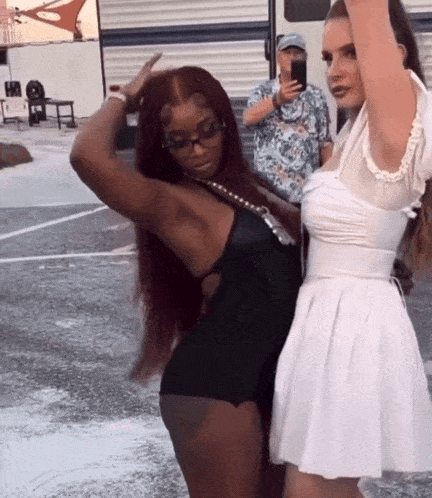 a woman in a white dress is standing next to a woman in a black dress