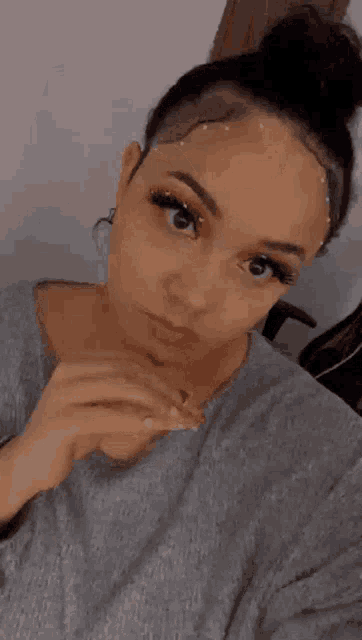 a woman is taking a selfie with her hair in a bun