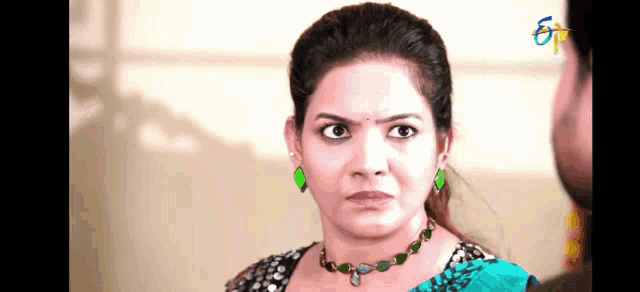 a woman wearing a necklace and earrings looks angry at a man .