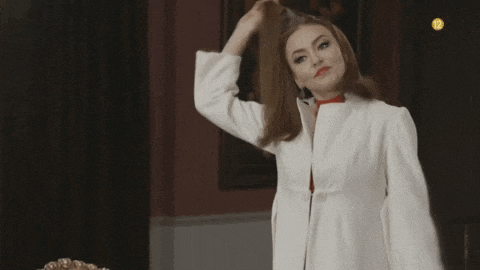 a woman in a white coat with a red bow tie is standing in front of a chair .