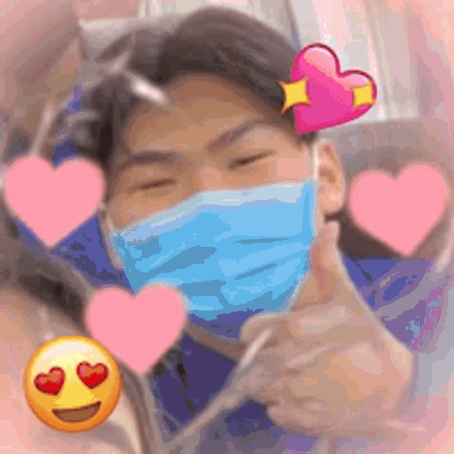 a man wearing a face mask is giving a thumbs up with hearts around him .