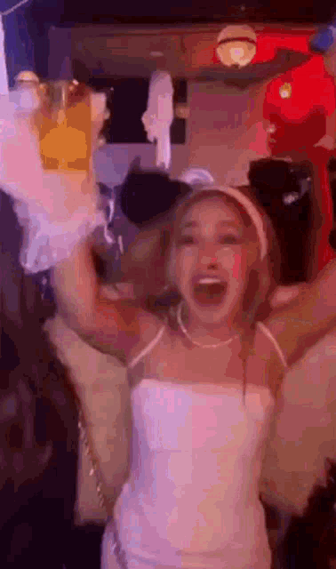 a woman in a white dress is holding a bottle of champagne in her hand in a crowded room .