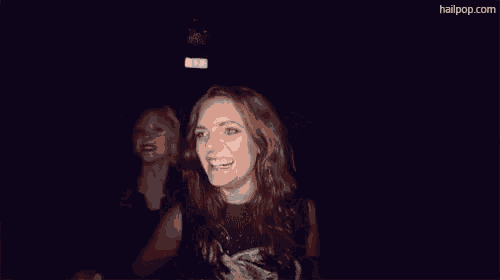 a woman in a silver jacket is laughing and touching her head .