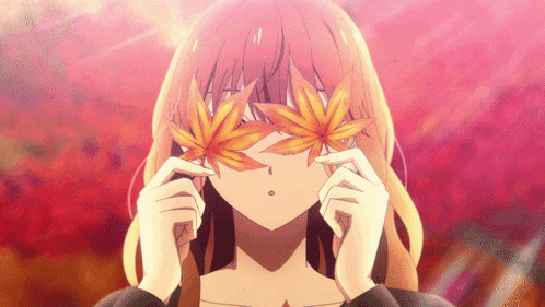 a girl is covering her eyes with leaves in her hands