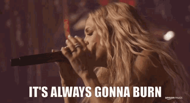 a woman singing into a microphone with the words " it 's always gonna burn " above her
