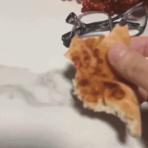 a person holding a piece of food with a pair of glasses on top