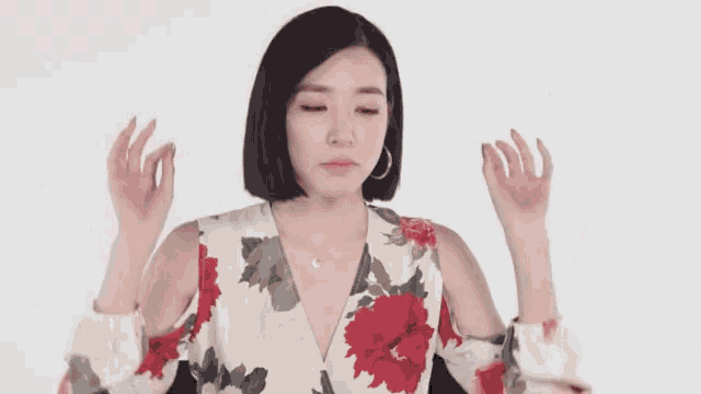 a woman in a floral dress is making a face with her hands