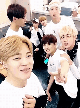 a group of young men are posing for a picture together and one of them is pointing at the camera