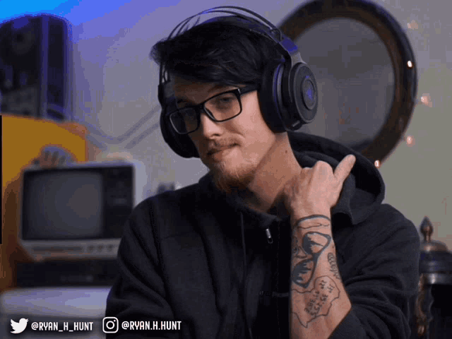 a man wearing headphones and glasses has a tattoo on his arm that says " i 'm sorry "