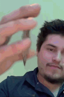 a man in a blue shirt is holding a small object in his hand .
