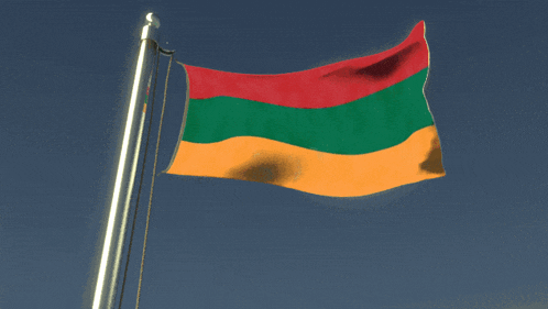 a red green and yellow flag is waving in the wind against a blue sky