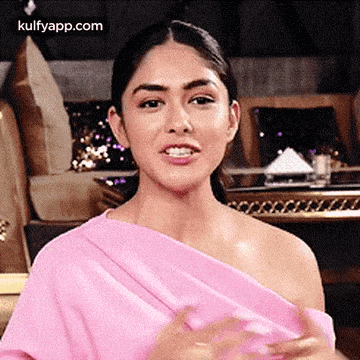 a woman in a pink dress is making a funny face and looking at the camera .