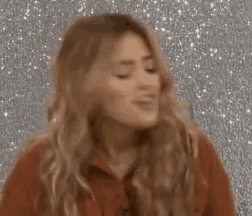 a woman in a red sweater is laughing and holding her hair in her hand .
