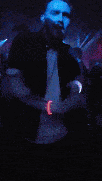 a man is dancing in a dark room with a blue light behind him