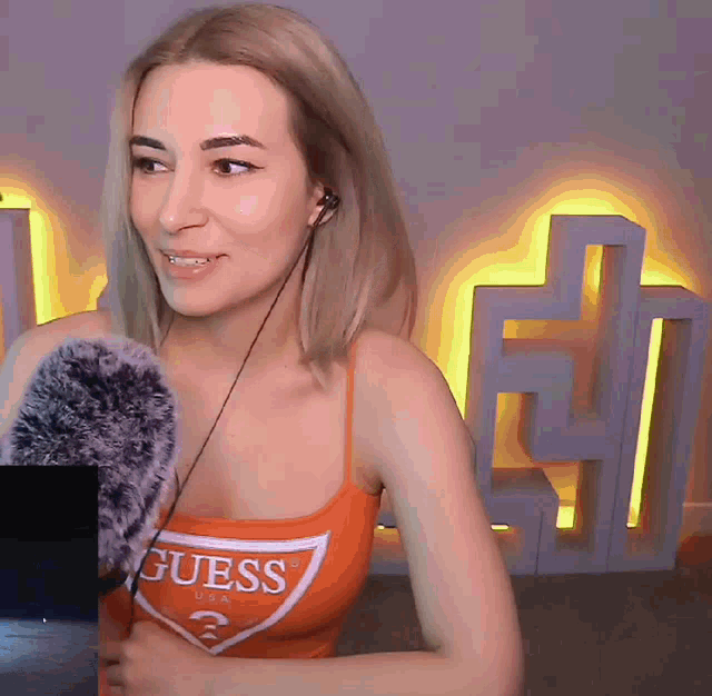 a woman wearing a guess tank top holds a microphone