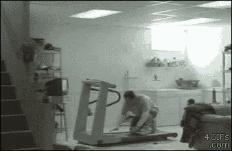 a man is kneeling on a treadmill in a basement in a room .