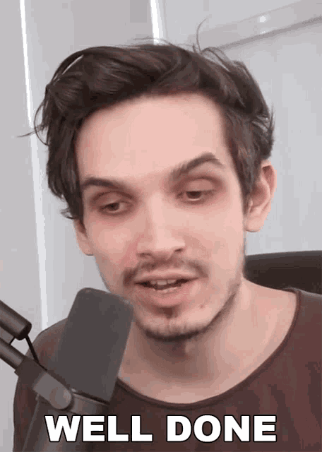 a man in front of a microphone with well done written on his face
