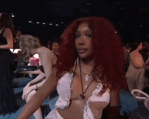 a woman with red hair is wearing a white dress and a necklace