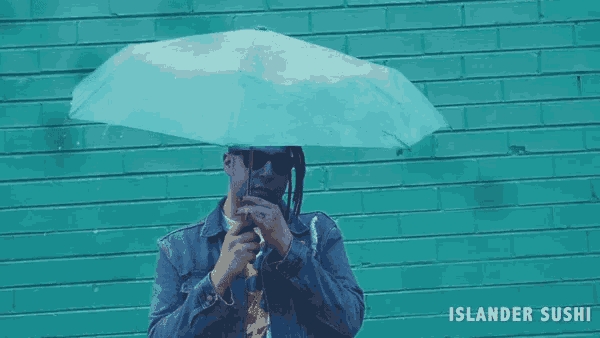 a man holding an umbrella in front of a green brick wall with islander sushi written below him