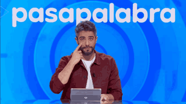 a man sitting in front of a blue background with the word pasapalabra