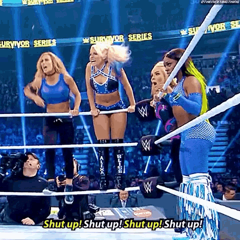 a group of women are standing in a wrestling ring and one of them is shouting shut up .