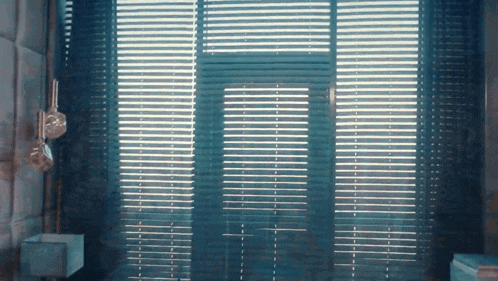 a window with blinds on it and a blue wall behind it