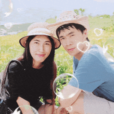 a man and a woman are posing for a picture in a field with soap bubbles around them