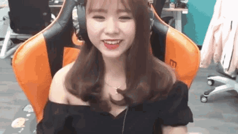 a woman is sitting in a gaming chair wearing headphones .