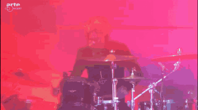 a man with a mask on his face is singing into a microphone with arte concert written on the bottom right