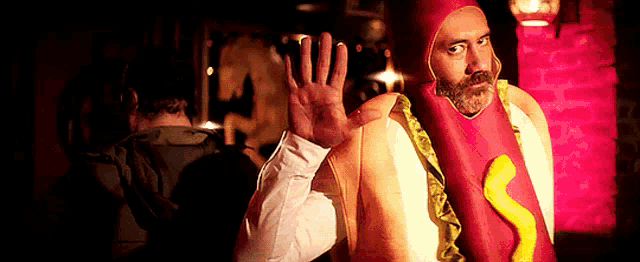 a man in a hot dog costume is waving