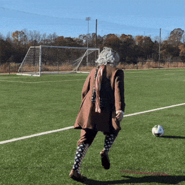 a man in a suit and tie kicks a soccer ball on a field