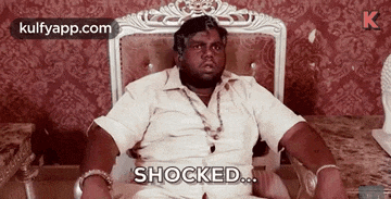 a man is sitting in a chair and saying `` shocked `` .