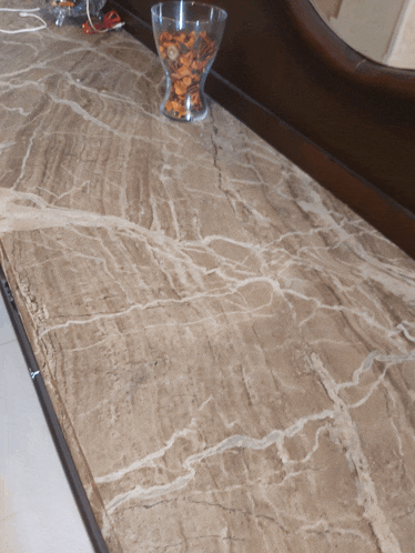 a marble counter top with a vase filled with nuts on it
