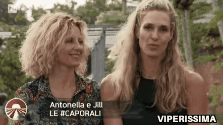 two women are standing next to each other and smiling in a video .
