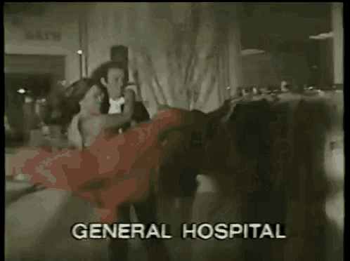 a man and woman are dancing in front of a general hospital