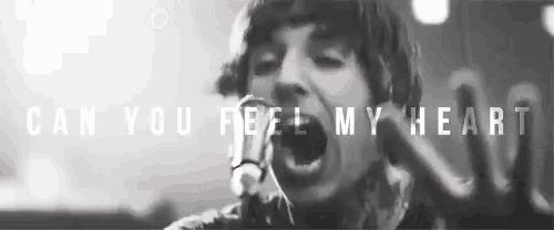 a black and white photo of a man singing into a microphone with the words can you feel my heart above him