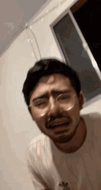 a man with glasses and a beard is crying with his eyes closed