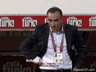 a man in a suit is standing in front of a cola turka banner