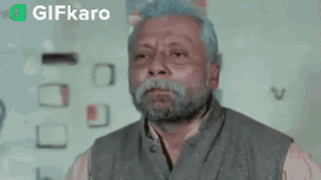 a man with a beard is making a funny face while standing in front of a wall .
