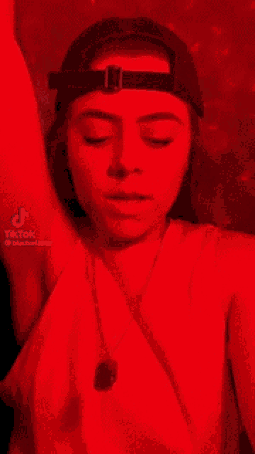 a woman wearing a hat and a necklace is standing in a red room .