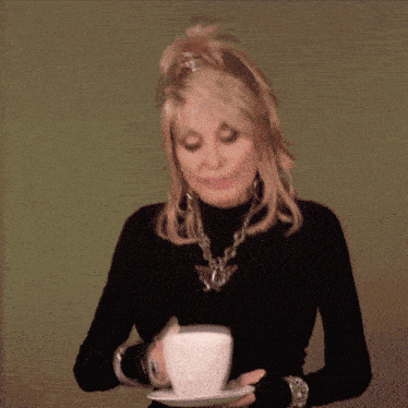 a woman in a black turtleneck is holding a white cup on a saucer