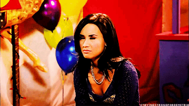 a woman sitting in front of balloons with the words stayingstrongfordemetria written below her
