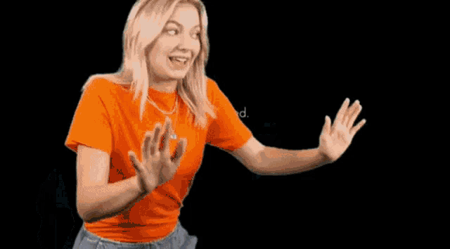 a woman in an orange shirt is standing in front of a computer
