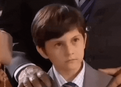 a young boy in a suit and tie is being held by a man in a suit and tie .