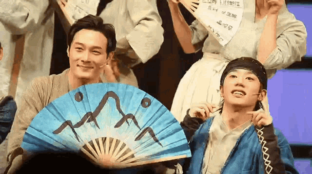 a man is holding a fan with a mountain on it