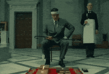 a man in a suit holds a cane while another man stands behind him