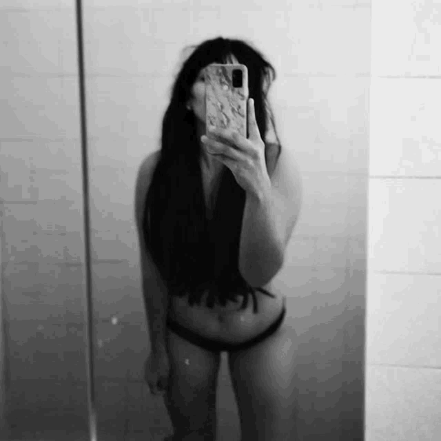 a woman in a bikini is taking a selfie in the mirror .
