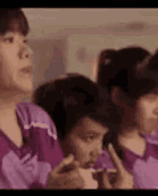 a group of people in purple shirts are sitting next to each other and talking .