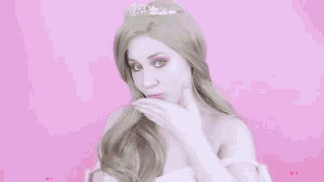 a woman in a princess costume is blowing a kiss with pink hearts in the background .