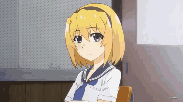 a girl with blonde hair and a blue tie is sitting in a classroom